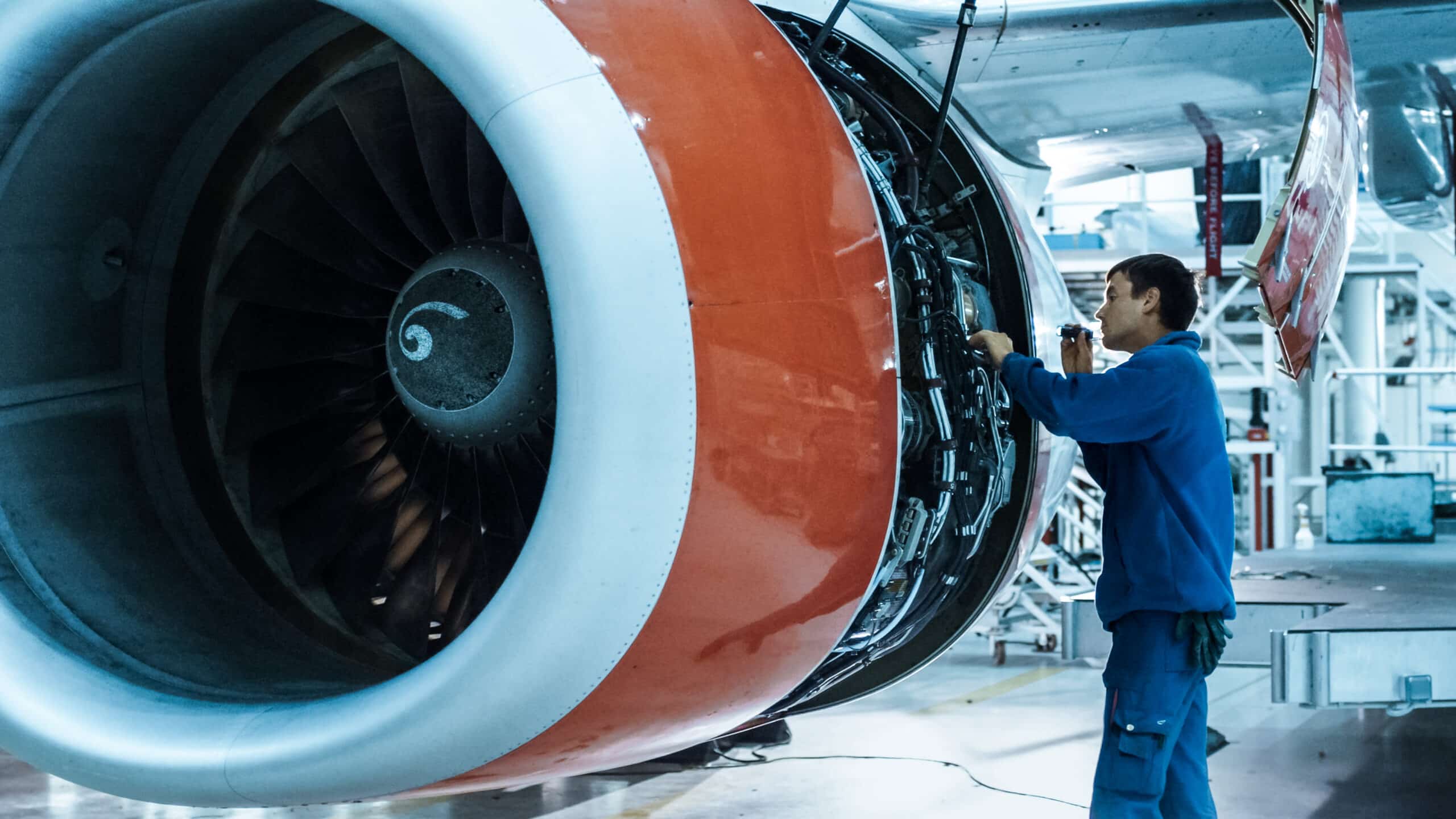 a man manually performing a visual inspection on an airplane engine